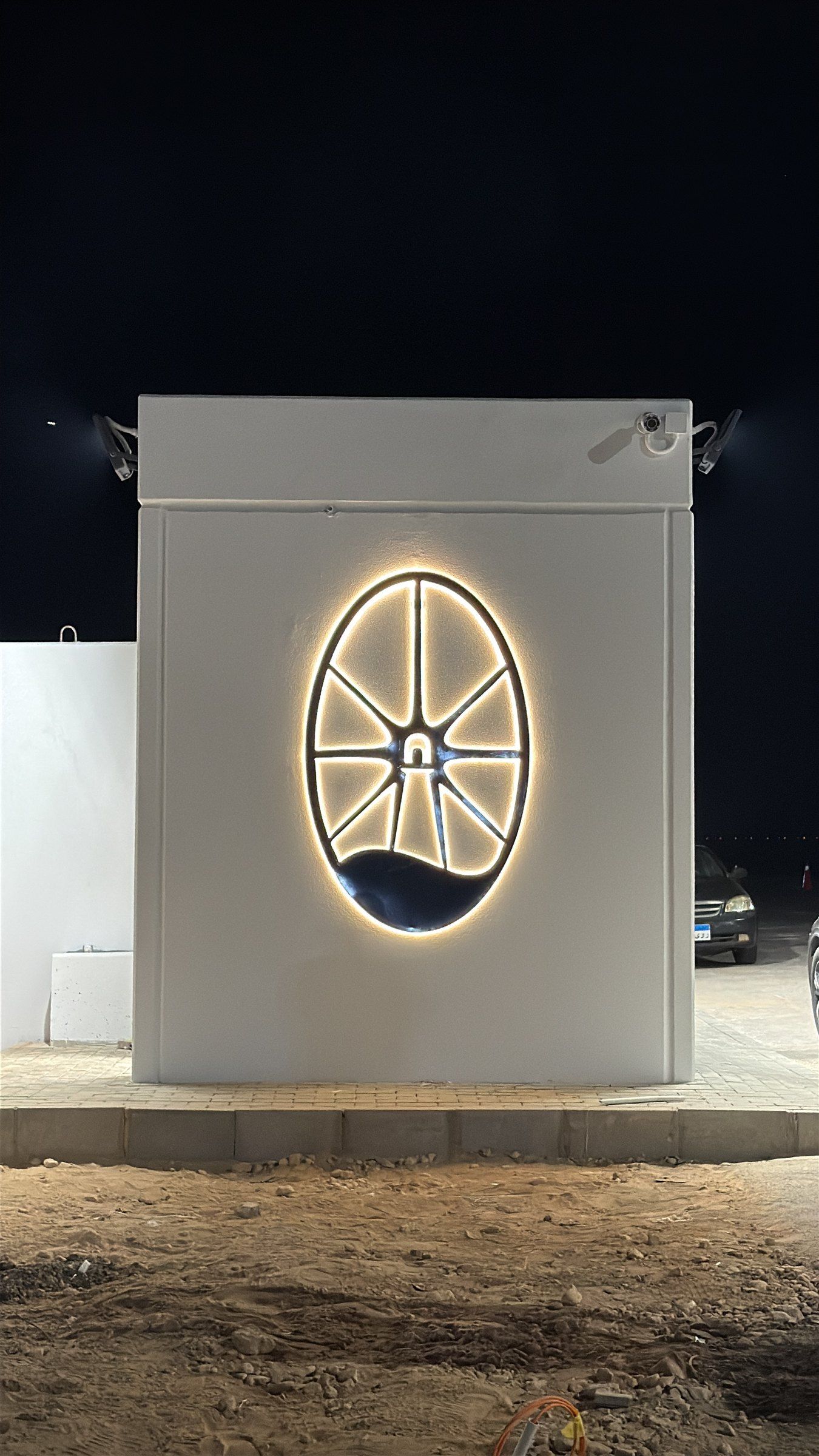 The development’s illuminated emblem on a gate pillar at night