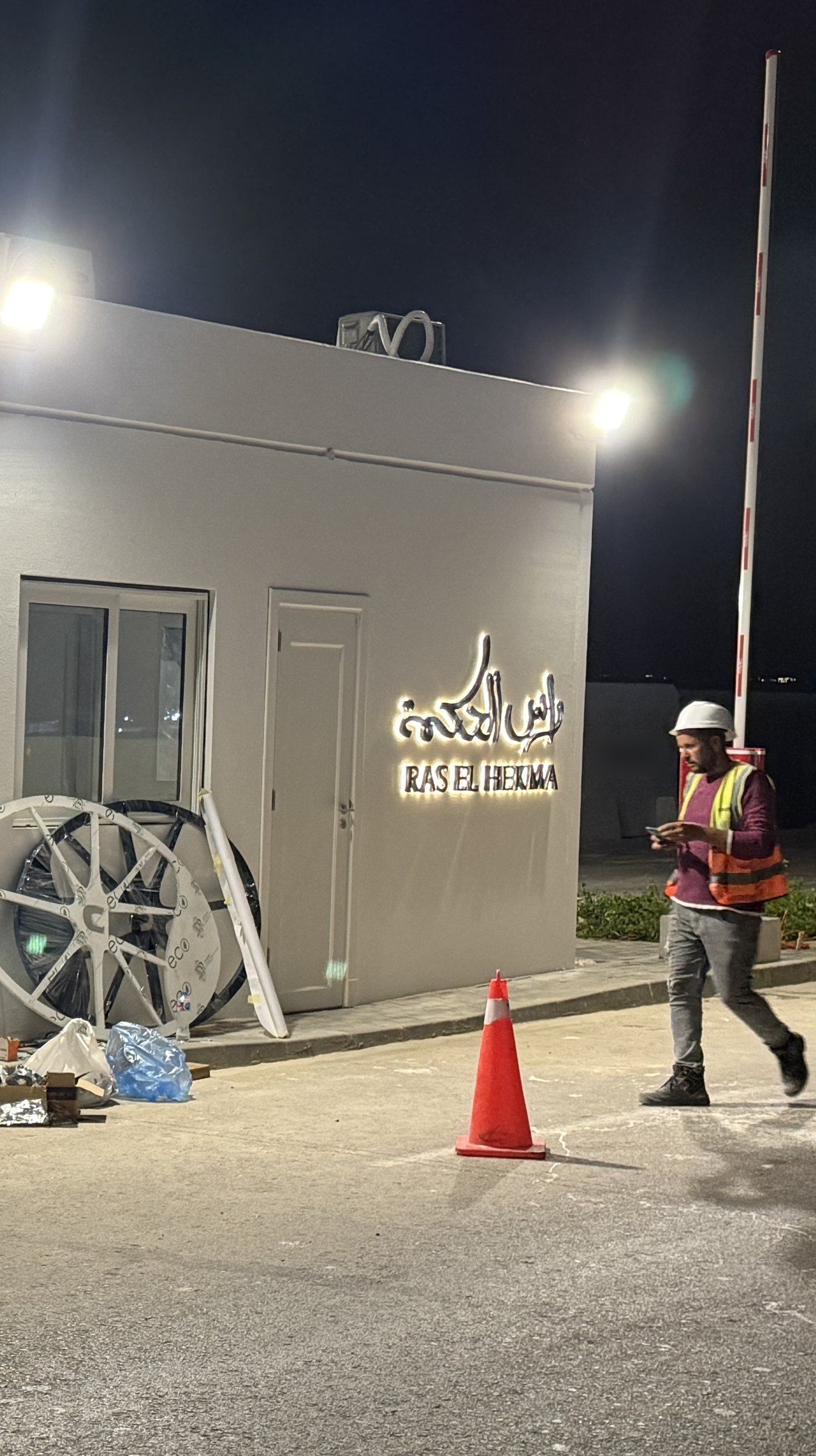 Technician in a hard hat and high-visibility vest at the gatehouse during night installation